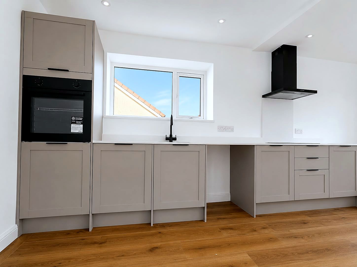 Fitted shaker kitchen with stone worktops and black handles